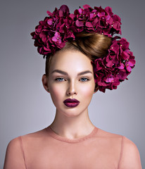 Young woman with a bouquet of purple flowers in her hair.