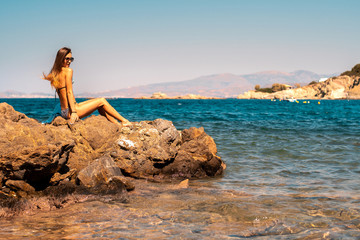 Wall Mural - young girl on the rocks by the sea