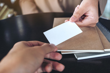 Businesswoman exchange business card with notebooks on table in office