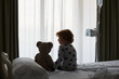 © Stocksy - Silhouette of a patient child sitting on a hospital bed with his teddy bear