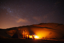 Group Of Friends Enjoying A Beach Camp Fire Under The Stars