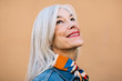 © Stocksy - Portrait of a cool senior woman with grey long hair smiling.