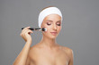 © Acronym - Beauty portrait of young and attractive woman with makeup brush.