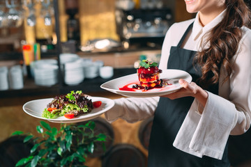 Waiter serving in motion on duty in restaurant. The waiter carries dishes