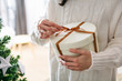 © Stocksy - Closeup of a woman unwrapping a gift for Christmas time.