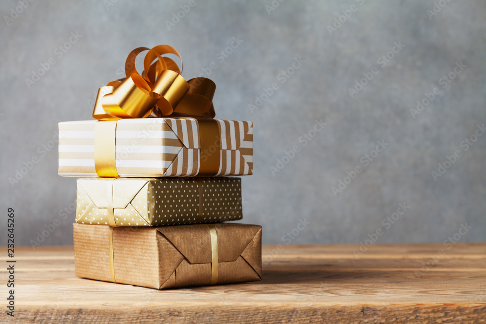Heap of golden gift or present boxes on wooden table. Composition for birthday or christmas. - obrazy, fototapety, plakaty 