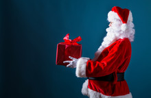 Santa Holding A Christmas Gift On A Dark Blue Background