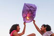 © Stocksy - Girls releasing chinese sky lantern to the sky at twilight