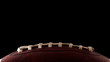 © Victor Moussa - American football and sports night event concept with close up on the laces of a leather ball isolated on black background with dramatic light lit from one side and copy space for text