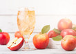 © DenisMArt - Glass of homemade organic apple cider with fresh apples in box on wooden background with sun light