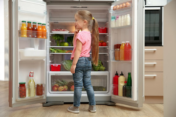 Sticker - Cute little girl choosing food in refrigerator at home