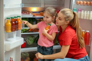 Sticker - Young mother and daughter choosing juice in refrigerator at home