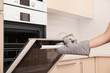 © New Africa - Woman opening electric oven door in kitchen, closeup