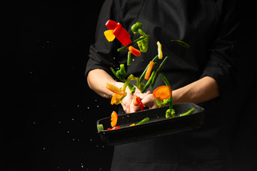 Professional cook. He prepares a dish with vegetables in a saucepan. on black background, menu, recipe book, healthy food