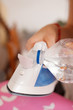 © Ivan - Close-up of a young woman filling laundry iron with distilled water. Doing house chores in apartment