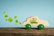 Concept of eco car. Wooden toy car with leaves and electric plug symbols impressed on the side.