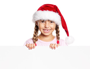 Wall Mural - Portrait of happy little girl in Santa hat with white blank. Child wearing Santa Claus hat, posing behind white panel. Kid holding empty Christmas billboard, peeping behind blank holidays board. 