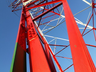 Detail of high voltage towers painted red on top of a mountain.