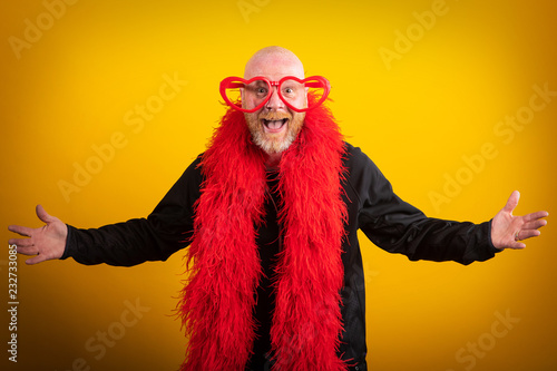 Fotografie, Obraz Portrait of man being funny with feather boa and heart shaped glasses