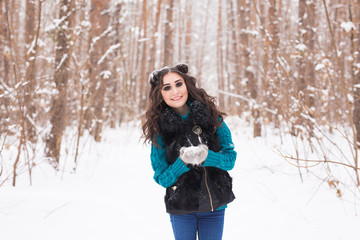 Young pretty woman walking in the winter snowy park at sunny day