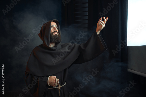 Fotomural Medieval monk praying against a window with light