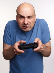 Poster - Angry bald man plays computer game isolated on grey studio background