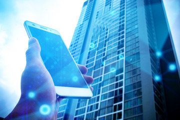 hand with phone mobile and building in network background with business concept
