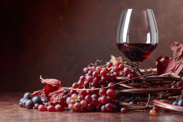 Red wine and fresh grapes with dried up vine leaves.