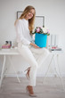 © Ulia Koltyrina - Stylish young blonde in office, white shirt and pants. Holds a luxurious bouquet of peonies in a blue hat box.