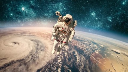 Wall Mural - Astronaut in outer space against the backdrop of the planet earth. Typhoon over planet Earth. Elements of this image furnished by NASA.