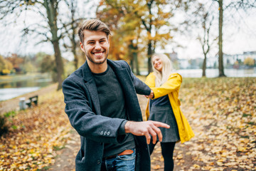 young couple having fun outdoors in autumn park, fall. Loughing and romp around