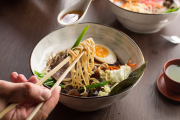 Wall Mural - Man eating Asian ramen with tuna and noodles in a restaurant