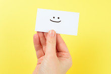 Smile Text On A Card In Woman Hand  On A Yellow Background.