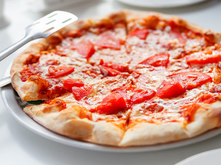 Pizza Margarita with baked ingredients - cheese with ham and tomatoes. Traditional italian cuisine.