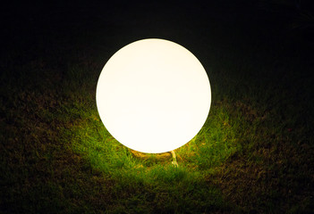 Glowing glass ball in the grass with black background