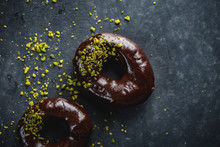 Two Doughnuts With Chocolate And Sprinkled Pistachios