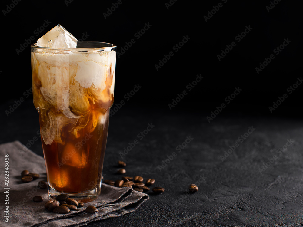 tall glass cold brew coffee with ice and milk on black or dark background - obrazy, fototapety, plakaty 