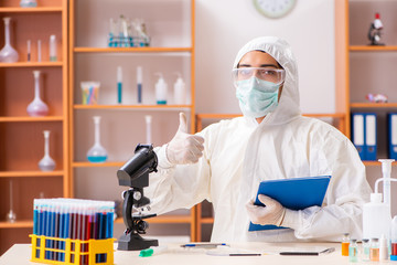 Young biochemist wearing protective suit working in the lab