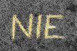 Słowo NIE napisane żółtą kredą na betonie. Bunt dziecka lub asertywność. 