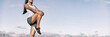 Runner stretching legs hamstring muscles outdoor holding one leg standing outdoor in sky background banner panorama. Running athlete woman doing fitness stretch.