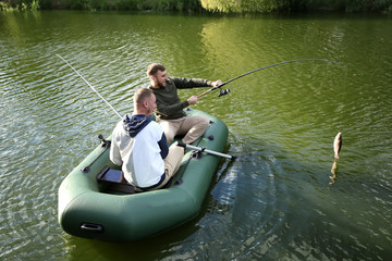 Friends fishing from boat on sunny day. Recreational activity