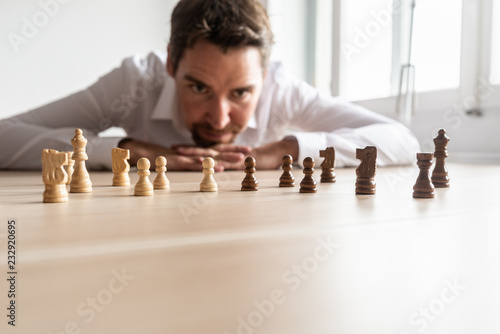 Fotografía Businessman looking at black and white chess pieces on office desk