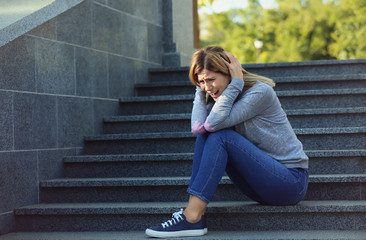 Wall Mural - Woman having panic attack while sitting on steps outdoors