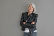 © goodluz - Modern senior woman in leather jacket on isolated grey background