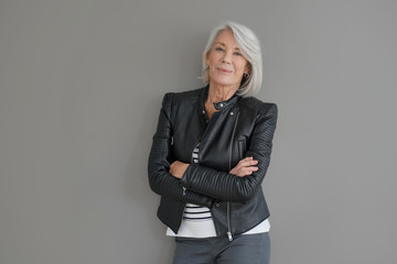 Wall Mural -  Modern senior woman in leather jacket on isolated grey background