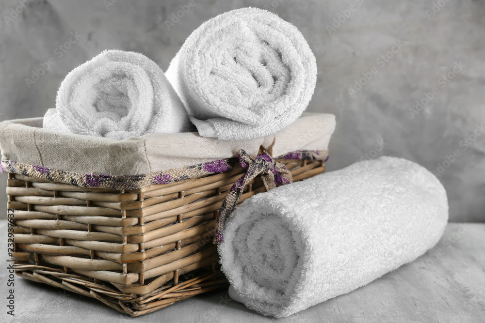 Wicker basket with soft towels on grey table