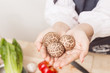 © chompoo - Young woman holding shiitake mushroom.