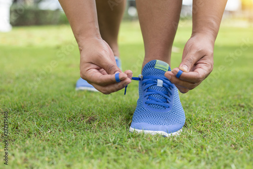 Fotografía Young woman runner tying shoelaces in lawn outdoors.