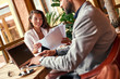 © Friends Stock - Business lunch. Man sitting at table working on laptop at restaurant while woman reading documents smiling cheerful close-up