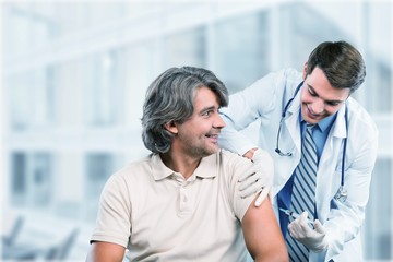 Wall Mural - Handsome doctor making vaccination to male patient on background